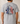 Person wearing a gray t-shirt with a graphic design on the back, featuring American flags and text.