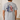 Person wearing a gray t-shirt with a graphic design on the back, featuring American flags and text.