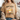 A woman wearing a beige graphic t-shirt with a cartoon sheep design and the text 'SORRY TO THE 99 I was dilly dallying', styled with a chunky knit cardigan and denim shorts.