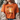 A woman wearing a burnt orange graphic t-shirt with a cute cartoon sheep design and the text 'SORRY TO THE 99 I was dilly dallying'. She is wearing a beige knit cardigan over the shirt, sitting on a couch.