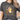A woman wearing a dark gray graphic t-shirt with a cartoon sheep character and the text 'SORRY TO THE 99 I was dilly dallying'.