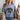 Woman wearing a light blue t-shirt with a humorous graphic design.