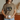 Person wearing a brown t-shirt with a graphic design holding a white mug.