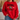A person wearing a bright red crewneck sweatshirt with a black and white football graphic on the front, paired with blue jeans in a cozy indoor setting.