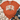 An orange short-sleeve graphic T-shirt laid flat on a white wood surface, styled with a knit blanket, blue jeans, and tan ankle boots. The shirt has a large white arched 'GAME DAY' print with black polka dots and a brown football graphic in the center.