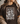 Person wearing a brown t-shirt with floral design and text