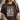 Person wearing a brown t-shirt with floral design and text