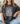 Person wearing a dark gray t-shirt with floral design and text, sitting on a couch.