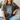 Person wearing a dark gray t-shirt with floral design and text, sitting on a couch.