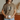 Person wearing a brown t-shirt with 'Jesus All Along' text, holding a mug indoors.