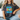 Person wearing a dark gray t-shirt with colorful text 'Sparkle Kindness Everywhere' sitting on a couch.