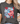 Person wearing a dark gray t-shirt with a smiley face design featuring American flag and flowers.
