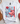 White t-shirt with a smiley face design featuring flowers and an American flag on a white surface.