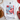 White t-shirt with a smiley face design featuring flowers and an American flag on a white surface.