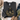 A folded dark gray crewneck sweatshirt with a graphic of a camouflage pumpkin and a black ribbon bow, styled in a flat lay with jeans, a hat, shoes, and flowers on a white wood background.