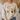 A person wearing a beige crewneck sweatshirt with a colorful graphic of nine cartoon chickens in various patterns, paired with blue jeans in a cozy indoor setting.