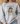 A woman wearing a light gray sweatshirt with a graphic of a frog wearing sunglasses and holding a coffee mug, with the text 'First Of All Jesus Thinks I'm A Delight'.