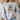 A woman wearing a light gray sweatshirt with a graphic of a frog wearing sunglasses and holding a coffee mug, with the text 'First Of All Jesus Thinks I'm A Delight'.