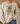 A person wearing a beige crewneck sweatshirt with a graphic of a frog in sunglasses holding a coffee mug, with the text 'First Of All, Jesus Thinks I'm A Delight'.