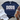 Navy blue t-shirt with 'DOGS Make Everything Better' text on a wooden surface with white shorts and brown sandals.