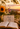 A warm autumn lifestyle scene at sunset featuring an open book, a mug that reads 'Choose Joy Everyday', a small pumpkin, a sign reading 'Made from Joy', and a floral arrangement in a vase on a wooden surface with a cozy blanket.