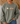 A person wearing an olive green crewneck sweatshirt with a graphic of four small cartoon characters on the chest, paired with blue jeans in a cozy indoor setting.