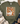 An olive green graphic t-shirt featuring a white goose wearing orange heart-shaped sunglasses and a bow, holding an iced coffee with pumpkins and autumn leaves. The shirt is styled in a flat lay with a straw hat, denim shorts, a beige knit blanket, and eucalyptus leaves on a white brick background.