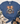 A blue short-sleeve graphic T-shirt laid flat on a light wood surface, styled with a scarf, jeans, and boots. The shirt features a raccoon illustration with a leopard-print bow, autumn leaves, pumpkins, and the text 'feral girl autumn'.