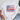 White t-shirt with a colorful pattern featuring a bow and flowers on a white surface.