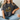 Person wearing a dark gray t-shirt with a graphic design of a frog and text, sitting on a couch.