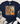 A navy blue graphic t-shirt with a distressed autumn design featuring the text 'God is Good ALL THE TIME', a pumpkin, and flowers. The shirt is styled in a flat-lay arrangement with a knotted hem, paired with distressed blue jeans, white sneakers, and a fringed throw blanket on a white wood background.