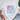White t-shirt with colorful graphic and text on a light wooden surface with shoes and jeans.