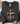 A dark charcoal gray Gildan sweatshirt laid flat on a white wood background, styled with a tan hat, jeans, shoes, and small floral accents. The sweatshirt features a colorful graphic of a cross wrapped in holiday lights with the text 'BE THE LIGHT' and 'Matthew 5:14'.