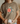 Person wearing a brown t-shirt with a turtle and flower design, holding a mug.