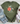 Green t-shirt with turtle and flower design, paired with jeans and sneakers on a wooden surface.