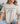 Person wearing a beige t-shirt with 'MADE FROM joy' text, sitting on a couch.