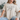 Person wearing a beige t-shirt with 'MADE FROM joy' text, sitting on a couch.