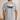 Gray t-shirt with a graphic of a man and his dog  in a boat on the back, set against a plain background.