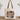 A canvas tote bag with brown leather handles sits on a wooden table against a white wall, decorated with eucalyptus branches. The bag features a large graphic print with a mountain illustration and the text 'MOUNTAIN MOVER' and 'MATTHEW 11:20-27'.