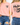 Pink t-shirt with 'Mustard Seed Faith' text on a person wearing blue jeans.