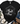 A black short-sleeve graphic T-shirt laid flat on a white wood background, styled with blue jeans, brown shoes, a cream throw blanket, and greenery. The shirt features a large black-and-white nativity scene print on the front showing Mary, Joseph, baby Jesus in a manger, and a donkey.