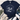 A navy blue short-sleeve t-shirt with a white graphic print of a nativity scene, styled in a flat-lay arrangement with distressed blue jeans, white sneakers, a fringed throw blanket, and green leaves on a light wood background.