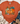 An orange short-sleeve graphic T-shirt laid flat on a white wood surface, styled with a knit blanket, blue jeans, beige ankle boots, and a small leaf sprig. The shirt features a large autumn pumpkin illustration with orange, teal, yellow, green, and floral details on the front.