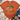 An orange short-sleeve graphic T-shirt laid flat on a white wood surface, styled with a knit blanket, blue jeans, beige ankle boots, and a small leaf sprig. The shirt features a large autumn pumpkin illustration with orange, teal, yellow, green, and floral details on the front.