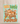 A cream canvas tote bag with brown shoulder straps stands on a wooden surface against a white wall. The front of the bag has a colorful autumn graphic with the text 'HEY THERE PUMPKIN' and an illustration of pumpkins, flowers, and leaves on a light blue background.