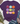 A purple short-sleeve T-shirt laid flat on a white wood surface, styled with jeans, loafers, a hat, and eucalyptus. The shirt has a large central graphic of nine colorful patterned pumpkins arranged in a 3x3 grid.