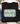A black crewneck sweatshirt laid flat on a white wood surface, featuring a retro-style graphic that reads 'SAVED BY GRACE' in cream lettering with pink and teal outlines. The sweatshirt is styled with jeans, a cup of coffee, a plaid scarf, and small flowers.