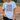 Person wearing a light blue t-shirt with 'Jesus Loves Softball' design on a baseball field.