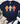 A navy blue graphic t-shirt laid flat on a white wood background, styled with a cream fringed throw, greenery, distressed blue jeans, and white sneakers. The t-shirt features three colorful glittery crosses (orange, light blue, and pink) with bows, and the text 'Grateful Thankful Blessed' and 'GOD IS FAITHFUL IN EVERY SEASON'.