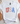 White t-shirt with 'USA' design on a white surface with shoes and decorative items.